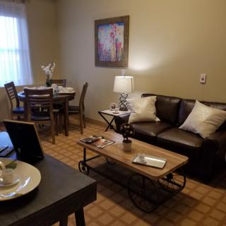 A cozy living room with a sofa, coffee table, and dining area.