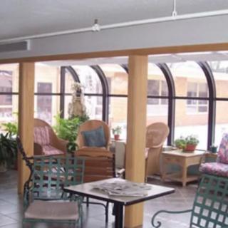 A cozy indoor seating area with wicker chairs and potted plants by large windows.