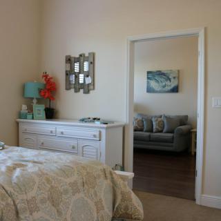 A cozy bedroom with a dresser and a view into a living area.