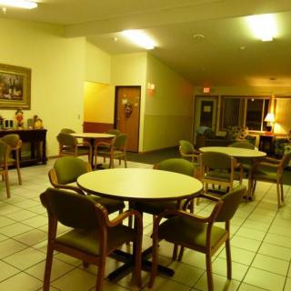 A well-lit dining area with several tables and chairs, featuring a tile floor and warm lighting.