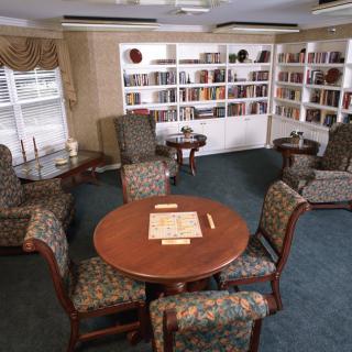 A cozy library corner with bookshelves and a table set for reading or board games.