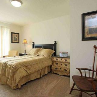A cozy bedroom with a double bed, bedside table, and a wooden chair.