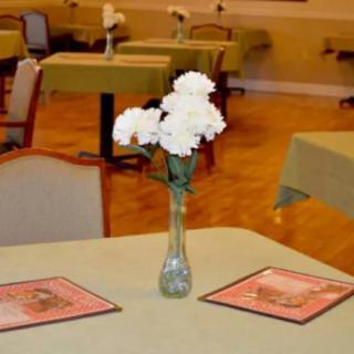 A restaurant table with white flowers in a vase and menus placed on it.