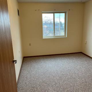 A vacant room featuring a window and neutral-colored walls.