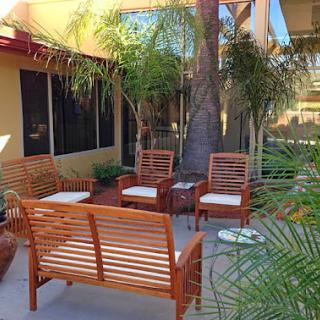 A cozy outdoor seating area featuring wooden chairs and palm trees, perfect for relaxation.