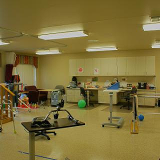 A spacious therapy room equipped with various exercise tools and office furniture.