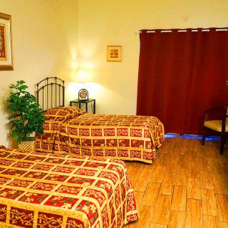 A cozy hotel room with twin beds and warm lighting.
