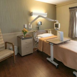 A well-equipped hospital room with a bed, medical equipment, and a chair.