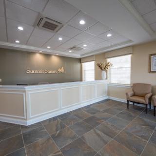 A modern office reception area featuring a sleek front desk and comfortable seating.