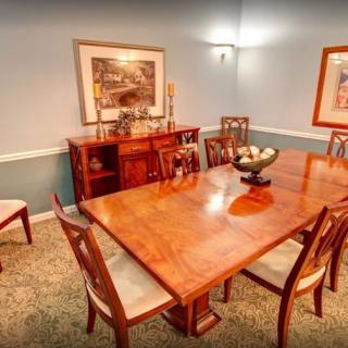 A well-furnished dining room featuring a wooden table, chairs, and decorative artwork on the walls.