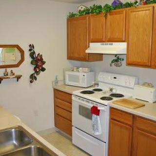 A small kitchen with wooden cabinets, a stove, and a microwave.
