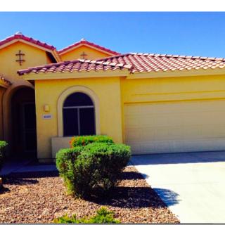 A suburban yellow house with a double garage and well-maintained landscaping.