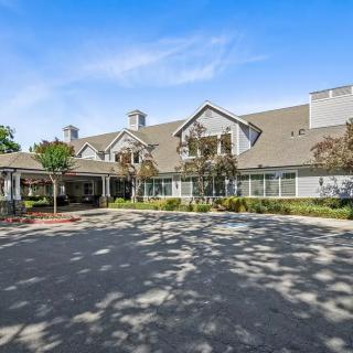 A suburban residential building with a large driveway and trees.