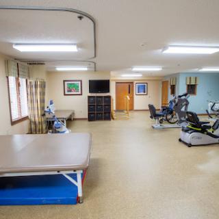 A spacious physical therapy room equipped with exercise machines and a treatment table.