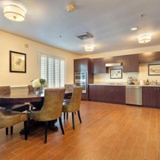 A modern dining and kitchen area with elegant furnishings and wooden flooring.