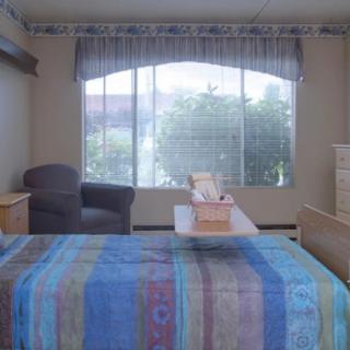 A cozy bedroom with a colorful bedspread and large window letting in natural light.