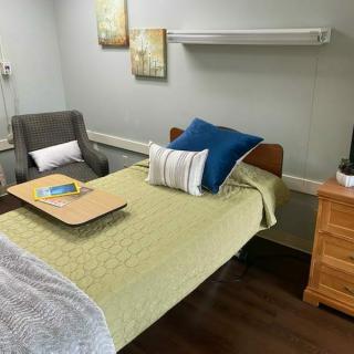 A cozy bedroom with a neatly made bed, adorned with pillows and a bedside table.