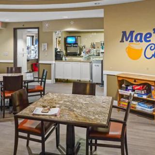 Interior view of a cafe with seating area, displaying tables, chairs, and a counter with coffee machines.