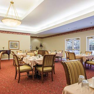 An elegant dining room with neatly arranged tables and chairs, featuring a chandelier and classic interior design.