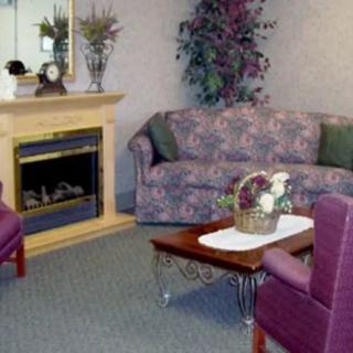 A cozy living room featuring a fireplace, floral sofa, and armchairs with a decorative coffee table.