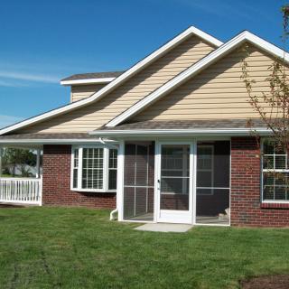 A suburban house with a well-maintained lawn and sliding glass doors.