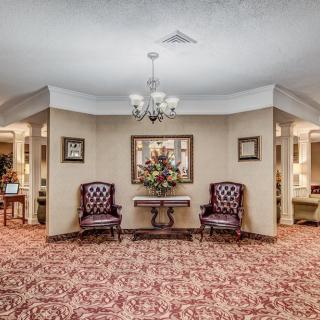 A traditionally decorated lobby area featuring elegant chairs, a chandelier, and a decorative table with flowers.