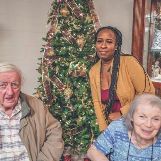 A family gathering in front of a decorated Christmas tree.