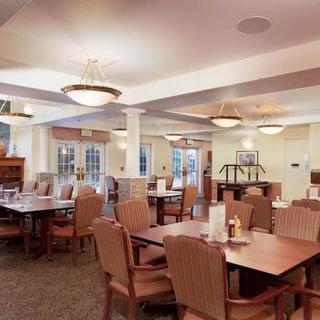 A spacious dining area with neatly arranged tables and chairs, illuminated by stylish ceiling lights.