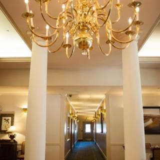 A luxurious hallway adorned with a grand chandelier and elegant columns.