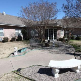 A backyard patio area with seating, a bench, and garden features.