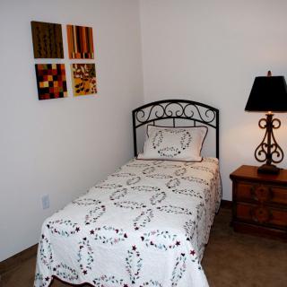 A minimalist bedroom with a single bed and bedside table with a lamp.