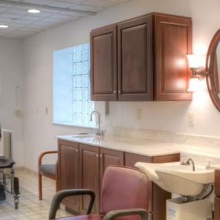 A well-lit hair salon interior with chairs, a washbasin, and cabinetry.