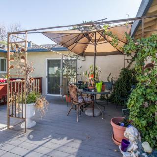 A cozy outdoor patio area with a large umbrella, surrounded by plants and decorative items.