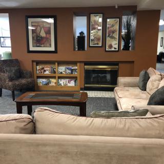 A cozy living room with a sofa, armchair, and a fireplace adorned with artwork.