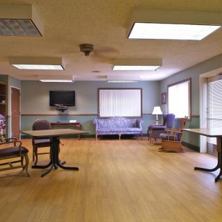 A spacious, well-lit room with chairs, tables, and a television.