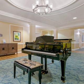A grand piano in an elegantly decorated lobby with a chandelier and carpet.