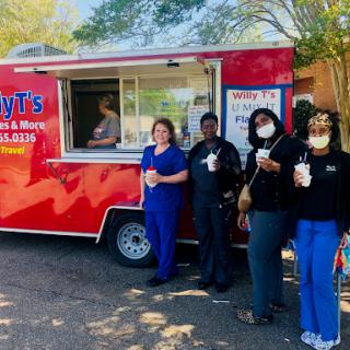 A group of friends enjoying drinks from a food truck on a sunny day.