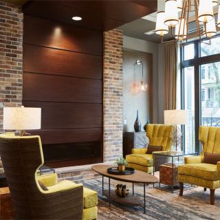 A cozy and modern lobby with stylish armchairs, brick wall accents, and elegant lighting.