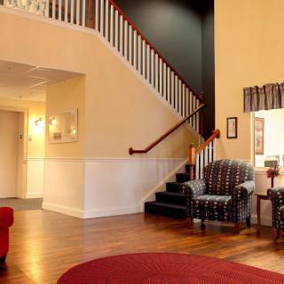 A cozy living room with a staircase, featuring comfortable seating arrangements and warm wooden flooring.