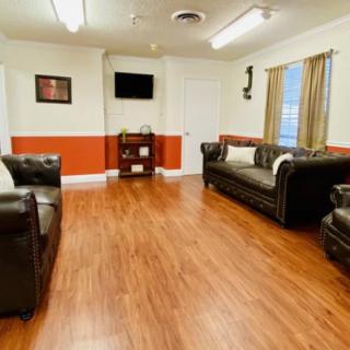 A cozy living room with leather sofas, wooden flooring, and a wall-mounted TV.