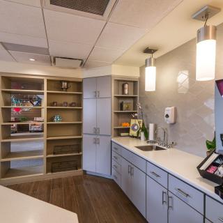 A modern office kitchen with sleek cabinets, open shelving, and pendant lighting.