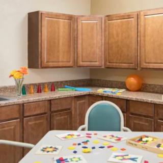 A kitchen area with wooden cabinets, a countertop, and a table set up for arts and crafts.