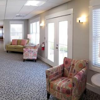 A cozy waiting room with patterned armchairs, a sofa, and large windows letting in natural light.