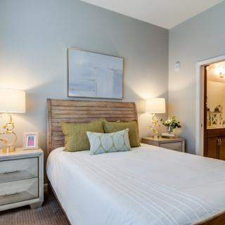 A cozy bedroom with a neatly made bed, two nightstands, and warm lighting.