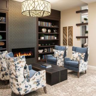 A cozy living room with floral armchairs and a modern fireplace.