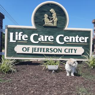 A welcoming sign for the Life Care Center of Jefferson City, accompanied by a pet in the foreground.