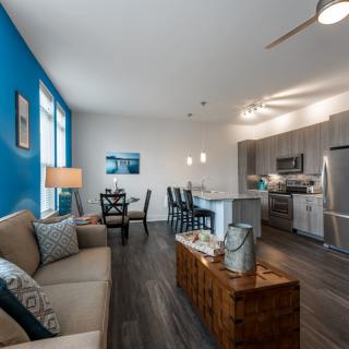 A modern open-concept living space featuring a cozy living room with a blue accent wall, a stylish kitchen, and a dining area.