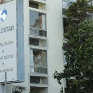 A building with a sign for the Goldstar Simulation & Training Center of America, surrounded by trees.