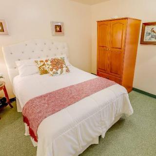 A cozy bedroom featuring a neatly made bed with a decorative pillow and a wooden wardrobe.