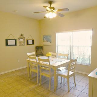 A cozy dining room with a wooden table and chairs, illuminated by a ceiling fan light.